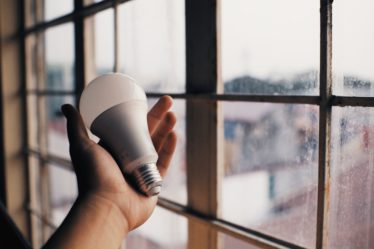 main qui tient une ampoule devant une fenêtre