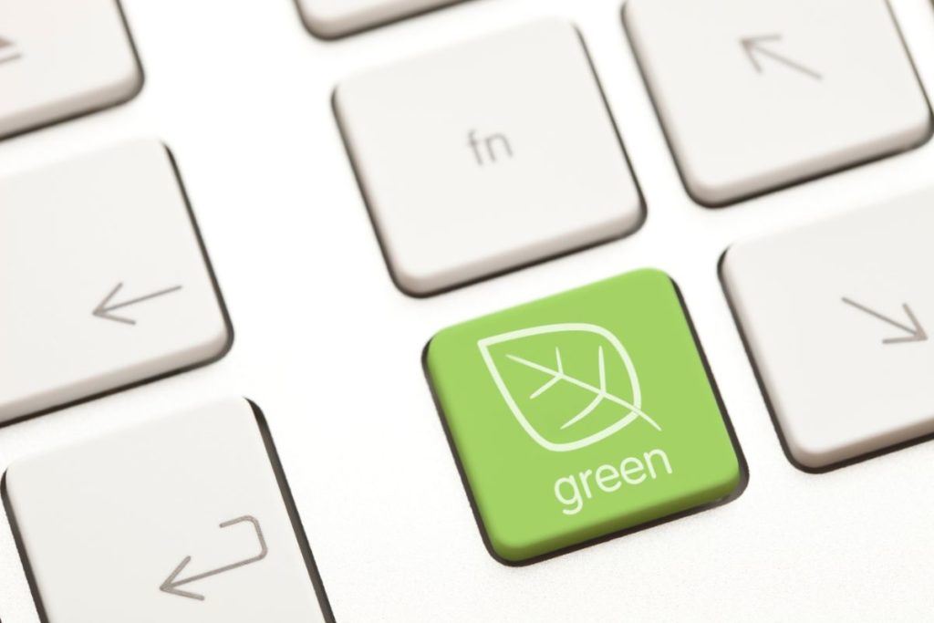 Clavier d'ordinateur blanc avec une touche verte sur laquelle se trouve une feuille d'arbre et le mot "green"